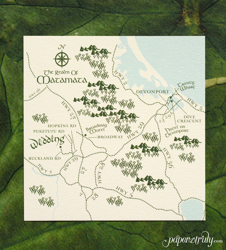 Op de afbeelding: Een handgetekend kaartje van Matamata, Nieuw-Zeeland, met een groen-wit kleurenschema. De kaart toont de locatie van de "Wedding" en het "Broadway Motel" met de tekst "The Realm of Matamata" bovenaan.
