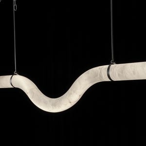 Może przedstawiać: Biała, zakrzywiona lampa wisząca z alabastru, zawieszona na czarnym przewodzie i łańcuchu. Lampa jest zawieszona na dwóch czarnych paskach.