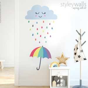 May include: A blue cloud with a smiling face is raining colorful raindrops onto a rainbow umbrella. The wall decal is perfect for a child's room.