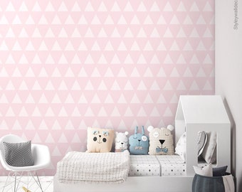 May include: A child's bedroom featuring a pink and white triangle patterned wallpaper. The room includes a white bed with star-patterned bedding, decorative pillows, and a white rocking chair. A wooden toy car and a grey basket are also present.