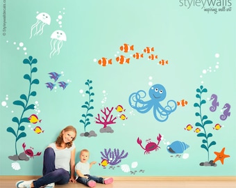 May include: A set of colorful ocean-themed wall decals featuring an octopus, seahorses, starfish, jellyfish, fish, coral, seaweed, and bubbles. The decals are shown on a light blue wall with a mother and child sitting in front of them.