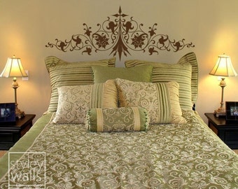 Puede incluir: Un edredón estampado en verde y blanco con una cabecera decorativa con un diseño floral marrón. La cama está hecha con varias almohadas en varios tonos de verde y blanco.