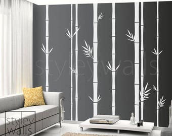 Può includere: Un muro grigio con un design di bambù bianco. Il muro è in un soggiorno con un divano grigio e un tavolino da caffè.