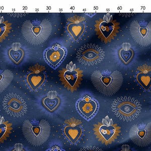 Op de afbeelding: Een donkerblauwe stof met een herhalend patroon van gestileerde harten, ogen en bloemmotieven in wit, goud en blauw. De harten hebben een stralend halo-effect.