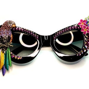 May include: A white ceramic mug with a black handle and the text "But First, Coffee" in a black, handwritten-style font. The mug is on a white surface.