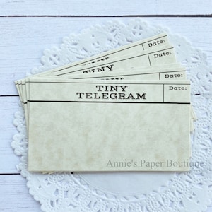 May include: A stack of blank, cream-colored cards with black borders and the text "TINY TELEGRAM" printed on the front. The cards have a line for a date at the top.