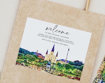 May include: Welcome to New Orleans, Louisiana! A brown paper bag with a sticker featuring a watercolor illustration of the St. Louis Cathedral and the text "Welcome to New Orleans, Louisiana! Thank you for traveling all this way. We can not wait to celebrate with you. With love, Michael and Emily."