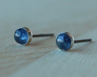 May include: A pair of silver stud earrings with small, round, blue gemstones.