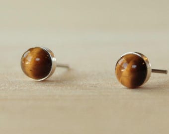 Puede incluir: Un par de pendientes de botón de plata con piedras redondas de ojo de tigre.