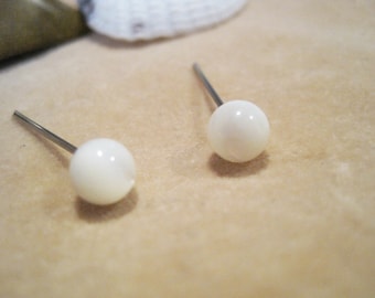 May include: A pair of white pearl stud earrings with silver posts.