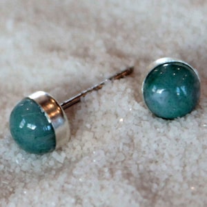 May include: A pair of silver stud earrings with round, teal-colored gemstones.