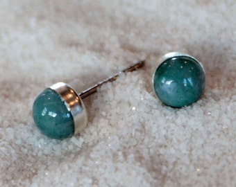 May include: A pair of silver stud earrings with round, teal-colored gemstones.