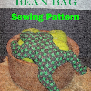 May include: A green frog bean bag sewing pattern with the text "Frog Bean Bag Sewing Pattern" and "Simple As Pie" on a brown burlap background.