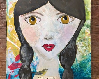 May include: A painting of a woman with long black hair and a red mouth. She has a small yellow bird perched on her shoulder. The painting has a colorful background and the text "Discover yourself" at the bottom.
