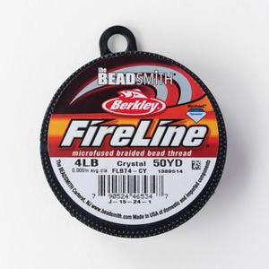 Może przedstawiać: Szpula mikrofuzowanej plecionej nici do koralików FireLine. Etykieta pokazuje markę, wagę 1,81 kg i długość 45,72 m. Szpula jest czarna z czerwonym, pomarańczowym i białym tekstem.