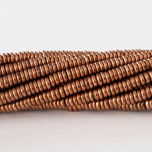May include: A close-up of a strand of copper-colored beads. The beads are round and have a smooth, shiny finish.