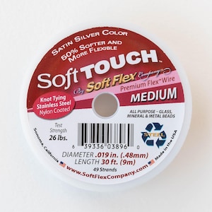 May include: A spool of silver Soft Touch by Soft Flex Company Premium Flex Wire in medium size. The spool is labeled with the product name, size, and material. It is made in the USA and has a test strength of 26 pounds. The diameter is 0.019 inches (0.48 mm) and the length is 30 feet (9 meters).