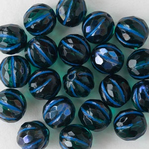 May include: A collection of dark green glass beads with blue stripes. The beads are faceted and have a shiny finish.