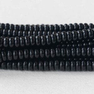 May include: A close-up of a strand of black beads. The beads are round and have a glossy finish.