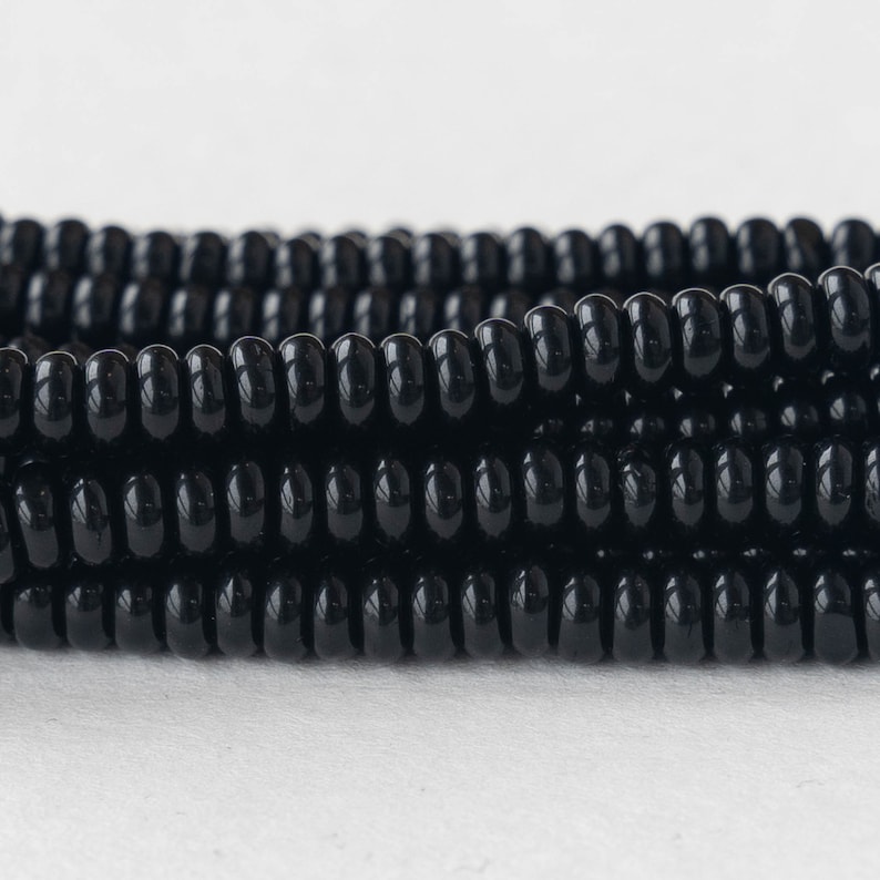 May include: A close-up of a strand of black beads. The beads are round and have a glossy finish.