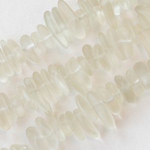 Pu&ograve; includere: Una collana di perline di vetro di mare bianco, ogni perla ha una forma unica e irregolare.
