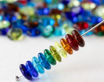 May include: A rainbow of glass beads strung on a wire. The beads are round and flat, and they are arranged in order of color, from red to violet.