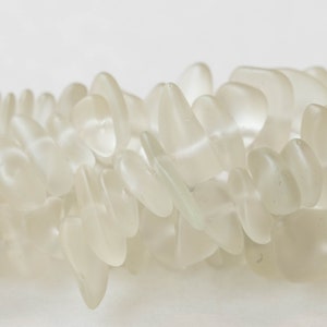 Pu&ograve; includere: Una collana di perle di vetro di mare bianco, ogni perla ha una forma unica e irregolare.