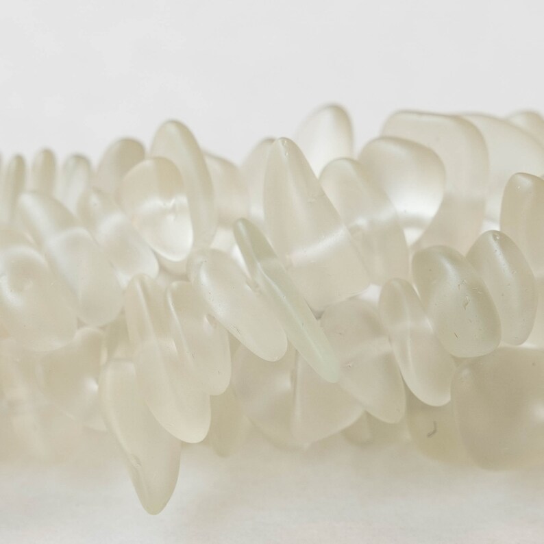 Pu&ograve; includere: Una collana di perle di vetro di mare bianco, ogni perla ha una forma unica e irregolare.