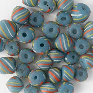 Puede incluir: Un conjunto de cuentas de vidrio azules con rayas coloridas en naranja, amarillo y blanco. Las cuentas tienen un agujero en el centro y presentan varias formas, incluyendo redondas, cuadradas y de barril. Ideales para la creación de joyas.