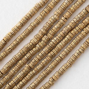 May include: A strand of gold-colored metal beads. Each bead is made of multiple stacked rings, creating a textured, geometric look.