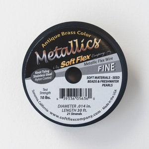 Puede incluir: Una bobina de alambre Soft Flex Metallics Fine de color bronce antiguo para hacer bisutería. La bobina está etiquetada con el nombre de la marca, el tipo de alambre y detalles sobre el alambre, incluyendo el diámetro, la longitud y el número de hebras. La etiqueta también indica que el alambre está hecho en los Estados Unidos y es adecuado para cuentas de semillas y perlas de agua dulce.