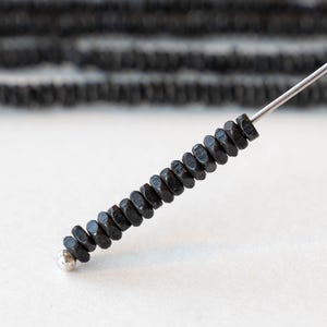 Peut inclure: Un brin de perles hexagonales noires enfilées sur un fil d'argent.