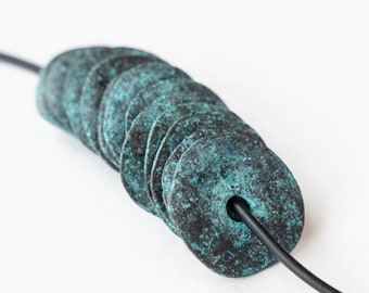 May include: A necklace with a series of stacked, round, teal-colored metal beads. The beads have a distressed, aged look and are strung on a black cord.