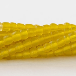 May include: A strand of yellow glass beads. The beads are round and have a frosted finish.