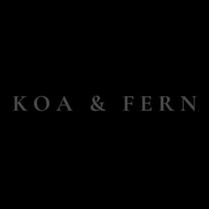 May include: A solid black background featuring the text KOA & FERN centered in the middle. The letters are rendered in a simple, clean, light gray serif font, standing out against the dark, uniform backdrop of the image.
