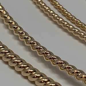 Peut inclure: Gros plan sur trois chaînes en or torsadées de différentes largeurs. Les chaînes sont de forme torsadée.