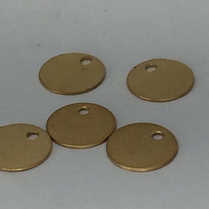 May include: Five gold-colored metal discs with a small hole in the center. The discs are round and have a smooth surface.