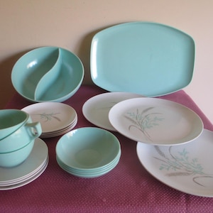 May include: A set of vintage turquoise and white melamine dinnerware with a floral design. The set includes a serving platter, salad bowls, dinner plates, and soup bowls.