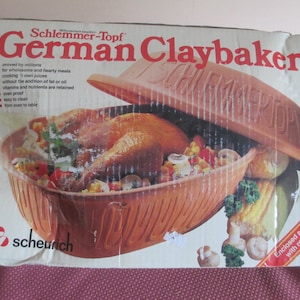 May include: A rectangular cardboard box for a Schlemmer-Topf German Claybaker. The box features a large image of a cooked chicken with vegetables in a terracotta-colored clay baker with a lid. Text includes brand names and cooking benefits.