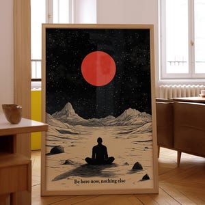 Op de afbeelding: Een zwart-witte illustratie van een persoon die in meditatieve houding op een woestijnlandschap zit, met een grote rode maan aan de hemel. De tekst "Be here now, nothing else" staat onderaan de afbeelding.
