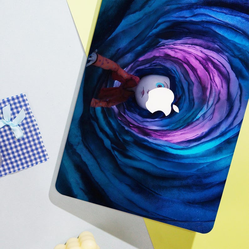 May include: A laptop skin featuring a whimsical illustration of a character falling into a swirling vortex of blue and purple hues. The Apple logo is integrated into the design. A small gift box with a blue and white checkered pattern is in the corner.