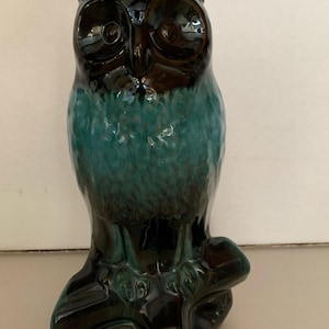 May include: A ceramic owl figurine with black and green glaze. The owl is perched on a branch and has large, round eyes.