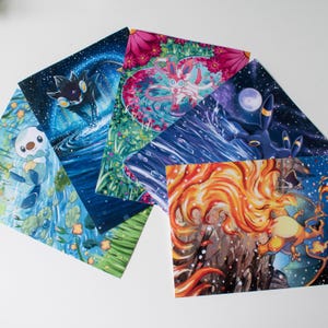 May include: A collection of colorful art prints featuring various Pokémon characters. The prints showcase vibrant illustrations with detailed backgrounds, including water, space, and floral elements. Each print displays a different Pokémon in dynamic poses.