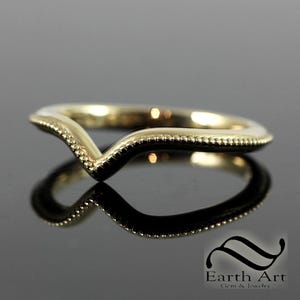 Może przedstawiać: Złota obrączka ślubna z wzorem w kształcie litery V i ozdobnym brzegiem.