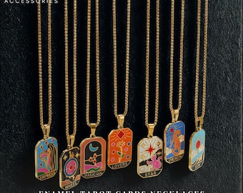 May include: Gold-tone necklaces with enamel tarot card pendants. Each pendant features a different tarot card design in vibrant colors. The text "EMPRESS", "WHEEL", "MAGICIAN", "LOVERS", "STAR", "STRENGTH", and "SUN" are visible. The text "ENAMEL TAROT CARDS NECKLACES" is also visible.