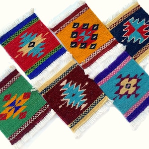 May include: A set of six rectangular woven coasters featuring vibrant geometric patterns in red, yellow, blue, green, and maroon. Each coaster is finished with white fringe on the top and bottom edges, showcasing intricate multi-colored designs.