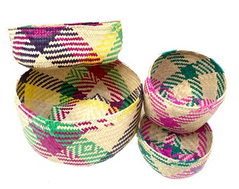May include: Set of four woven baskets with a colorful geometric pattern in shades of pink, green, yellow, and black. The baskets are made of natural materials and are perfect for storage or display.