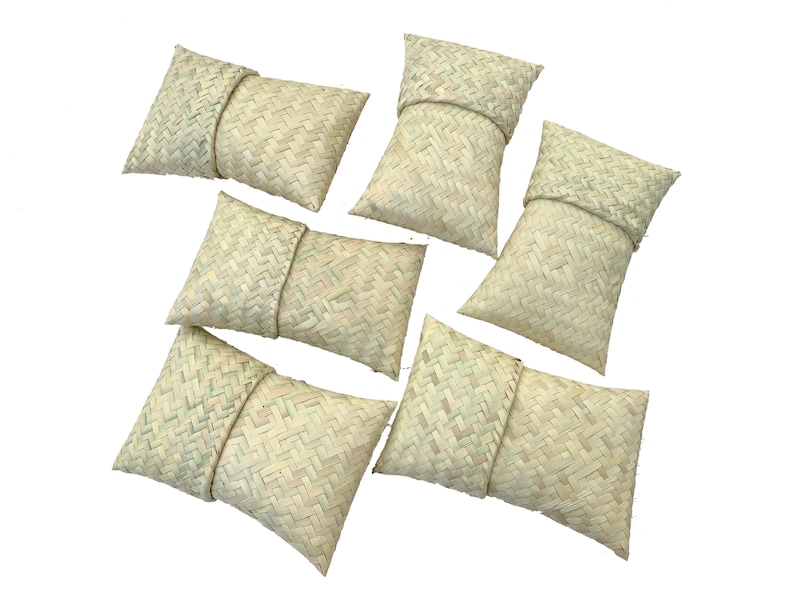 May include: Six woven straw pouches, each with a folded top, arranged in a scattered pattern on a white background.