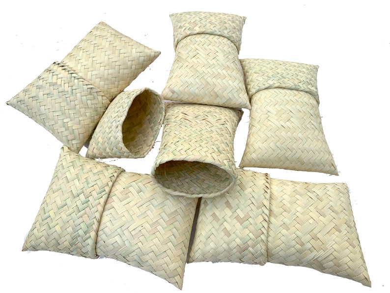 May include: A group of eight woven straw pouches, some are folded closed and some are open, showing the inside. The pouches are all made of a light beige straw.