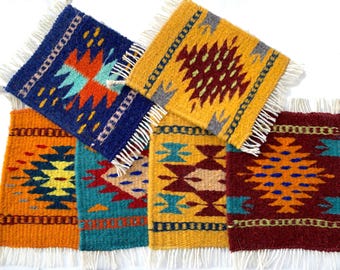 May include: A collection of five rectangular woven coasters featuring vibrant geometric patterns in shades of blue, yellow, orange, red, and teal. Each coaster is finished with white fringe along the top and bottom edges, showcasing intricate, multi-colored diamond and linear motifs.